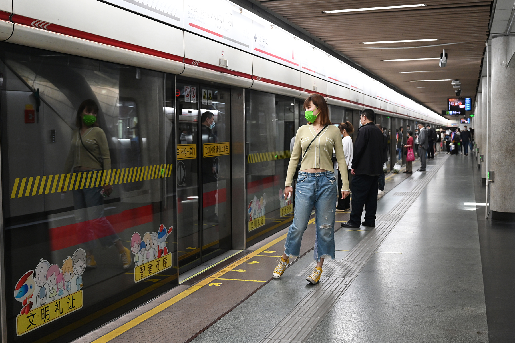 2023年5月25日，上海，地铁人民广场站。一女子凭借站台玻璃的反光整理仪表。澎湃新闻记者 吴栋 图