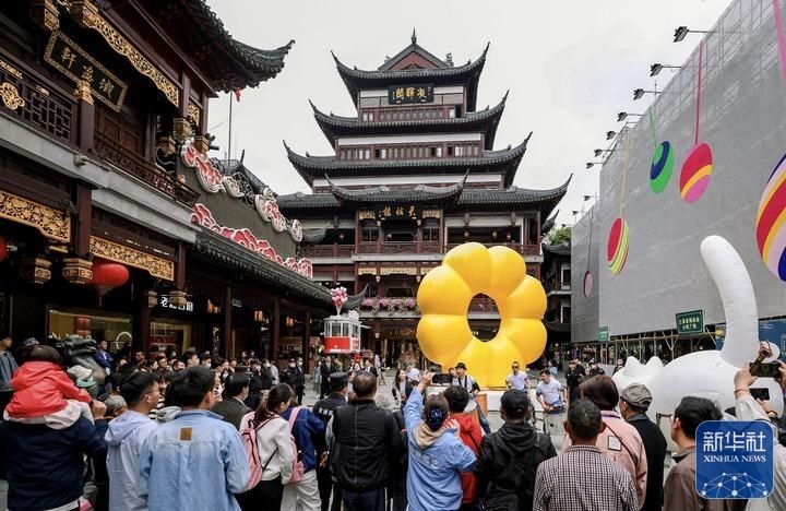 5月7日，市民游客在上海豫园商城中心广场观看街头艺术表演。新华社记者 刘颖 摄