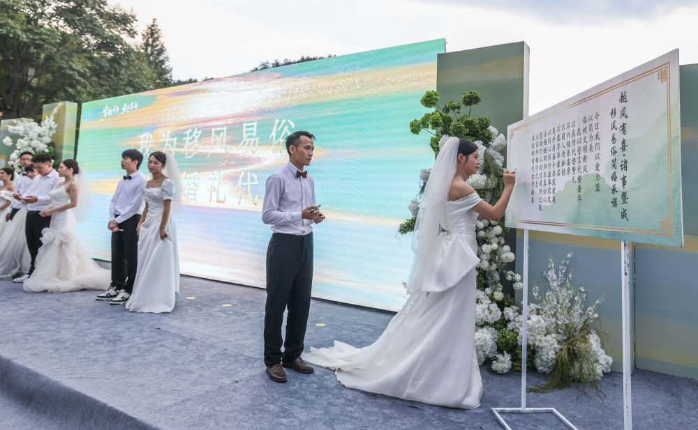 2025年8月20日,在浙江省诸暨市东白湖镇斯宅村举行的集体婚礼上,新人在移风易俗倡议上签名。新华社记者 徐昱 摄