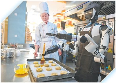 人形机器人与糕点师傅共同制作月饼。<BR/>新华社记者 金良快摄