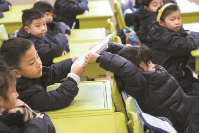 新课本发放,一名学生正在传递新课本。均为 赖鑫琳 摄