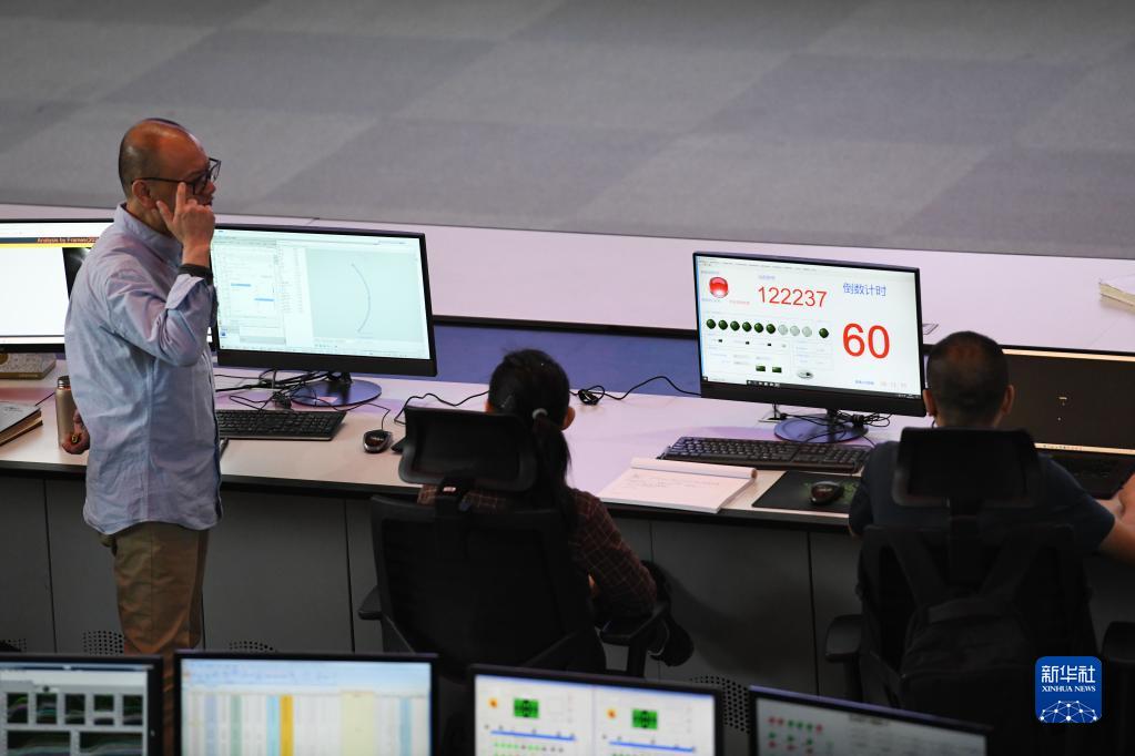 4月12日，EAST物理实验总负责人龚先祖（左一）在实验过程中与同事交流。新华社记者 张端 摄