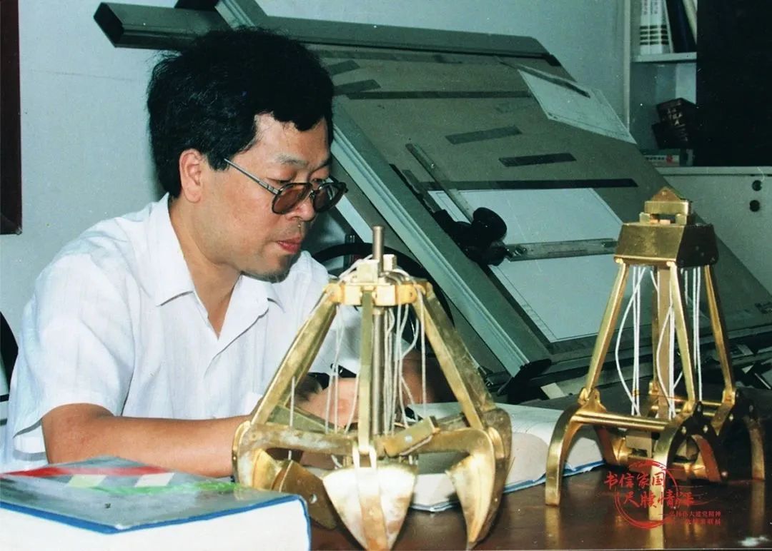 包起帆在工作中，桌上放着的是他发明的抓斗的模型