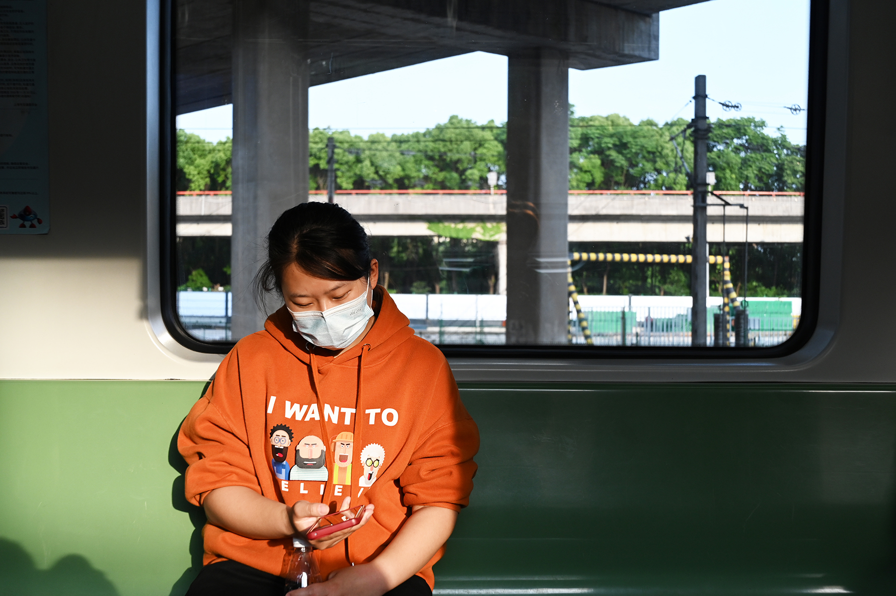 2023年5月25日，上海。地铁一号线车厢里，一名女子正看着手机，阳光洒在地铁里。澎湃新闻记者 吴栋 图