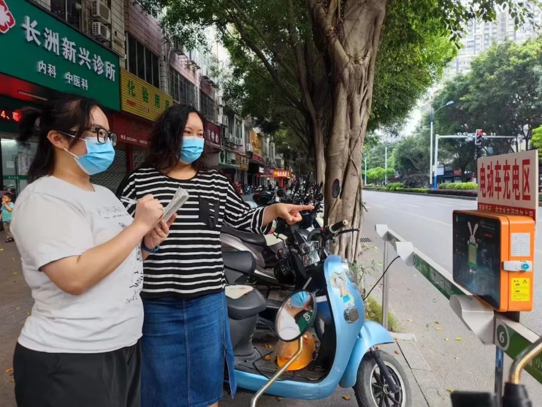 2023年5月22日,市政协委员范舒舒(右)、梧州日报记者钟慧(左)在新兴二路对人行道两轮车充电桩是否规范等问题进行回访、调研。(梧州市政协供图)