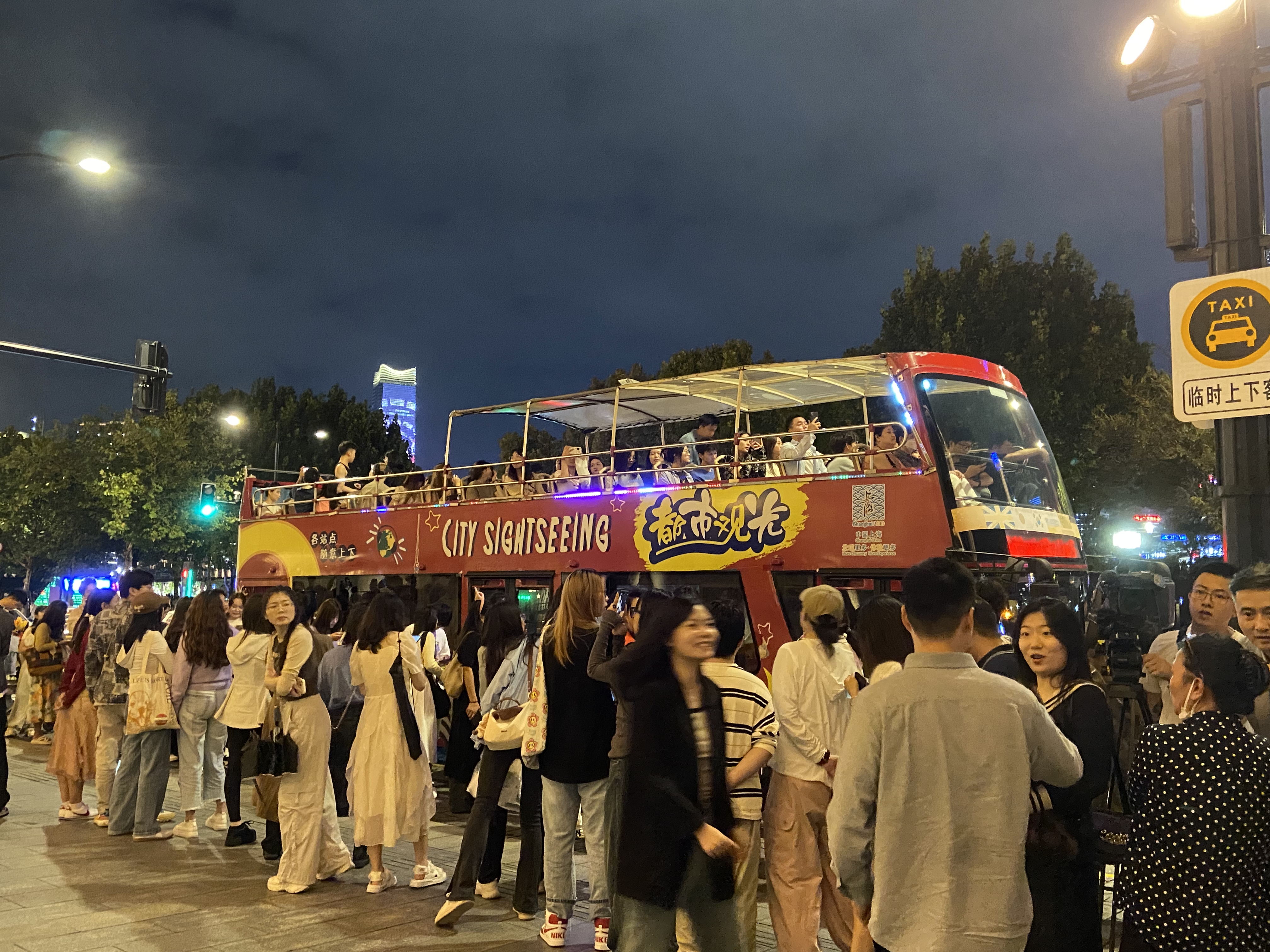 游客在外滩海关大楼站排队等待敞篷观光巴士。