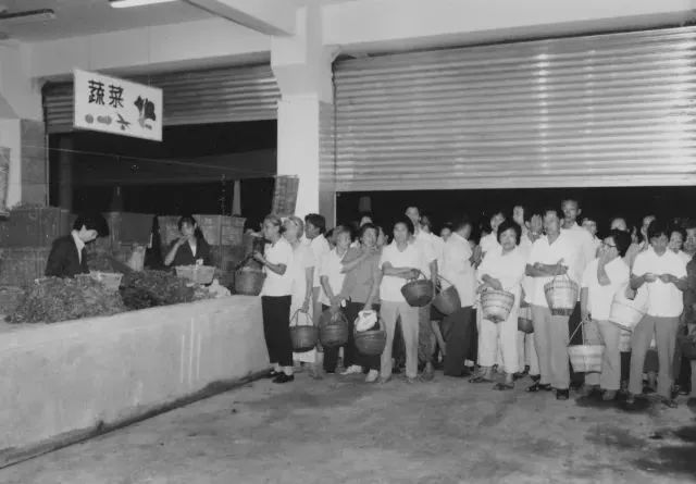 20世纪80年代,居民们清晨在菜市场门口排队等着5点开秤铃声响起