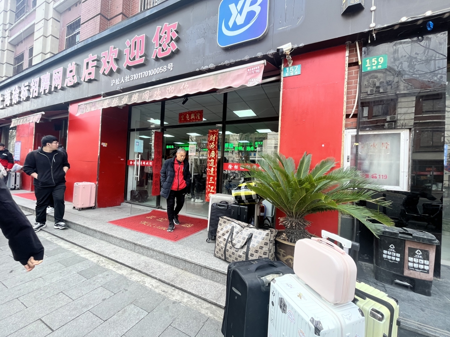 3月27日上午,松江车墩徐标劳务门口,许多人拖着行李箱来找工作。