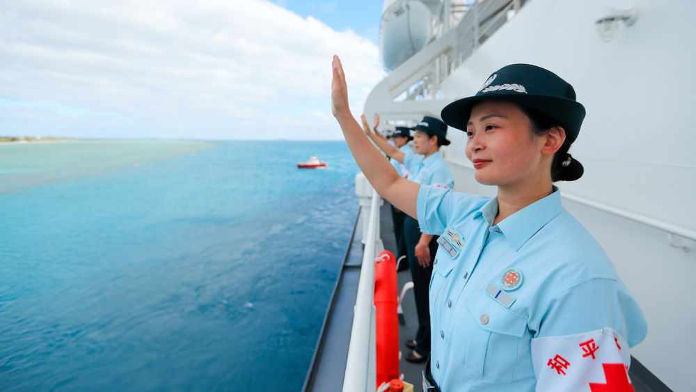 中国海军“和平方舟”号医院船结束访问汤加时,任务官兵中的文职人员向欢送人群挥手告别(2023年8月4日摄)。新华社发(徐巍 摄)
