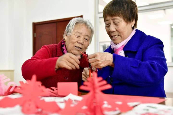 在山东省滨州市博兴县博华老年公寓文体活动室,老人们在剪纸。新华社记者 郭绪雷 摄