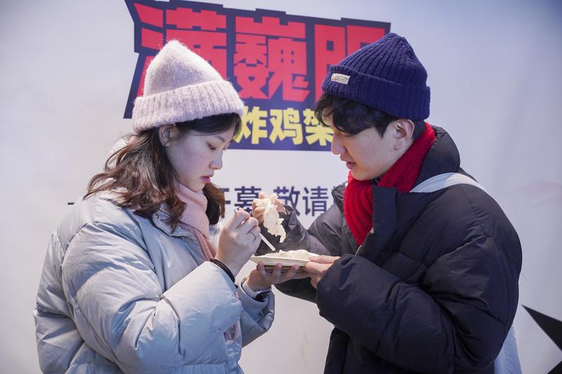 12月25日,韩国游客在上海豫园商城品尝美食。