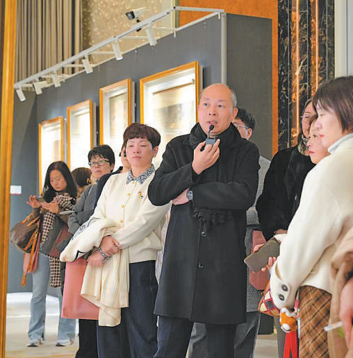 朱旗委员(中)正在为观众导览中国传统书画展。