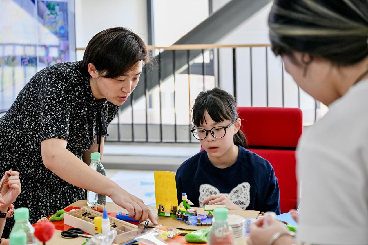 街道妇联主席张渝(左)和小学生代表沈嘉妮(中)互动