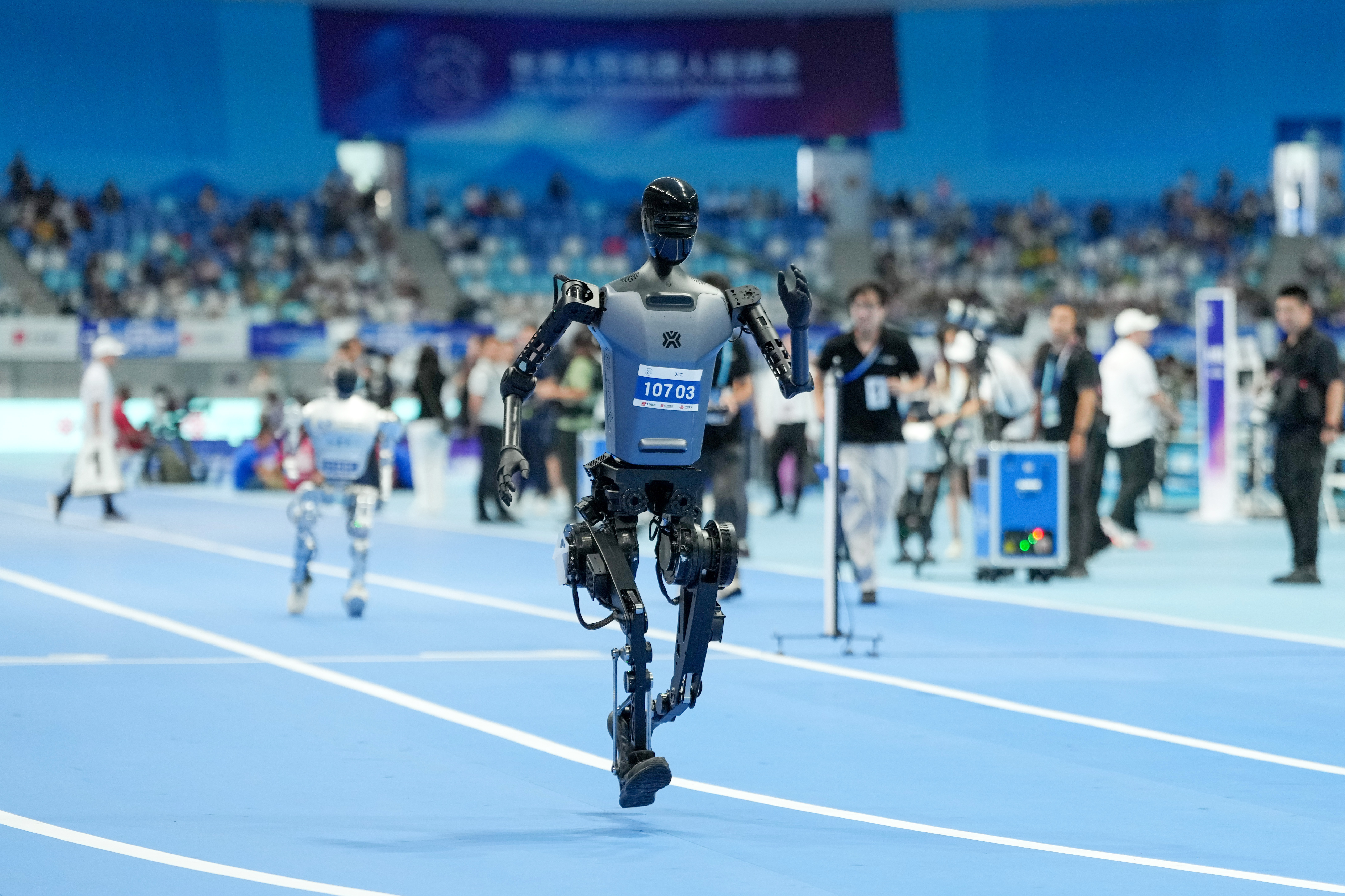 2025年8月17日,在世界人形机器人运动会4x100米接力决赛中,来自天工队的人形机器人(前)在比赛中。新华社记者 鞠焕宗 摄