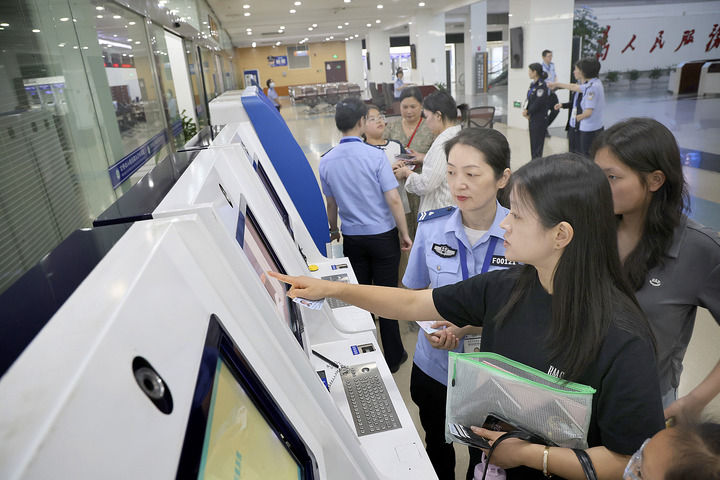 2025年6月25日，工作人员在江苏南通市政务中心出入境办证大厅指导市民使用自助填表系统。新华社发（许丛军摄）